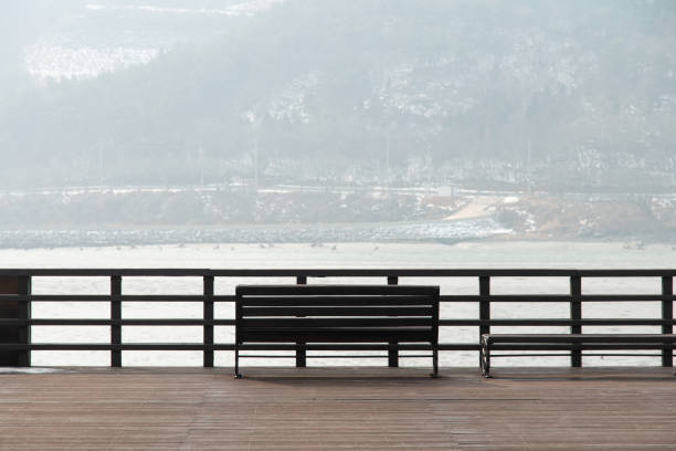 istock empty wooden bench at the riverside in winter 2162869603