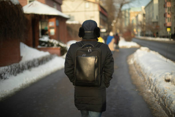 istock A man in black clothes on the street. Black backpack and jacket. Unknown man from the back. 2162870147