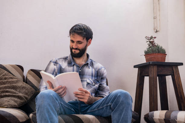 istock Mid adult man reading book at home 2162875087
