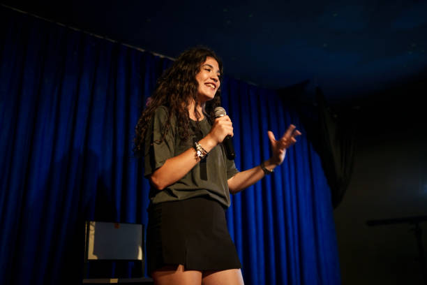 Young woman using microphone at stage, stand up comedian