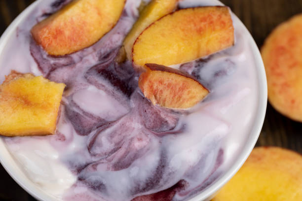 fresh yogurt with jam and pieces of ripe nectarine, natural yogurt in a white bowl with fruits