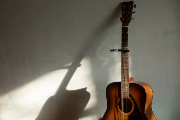 istock Acoustic guitar against wall. Old guitar in light from window. 2162882353