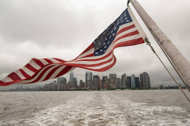 American flag, Ellis island boat, May 30, 2017,American flag waving at the back of the boat going to Ellis Island while the Manhattan skyline is visible at the back.