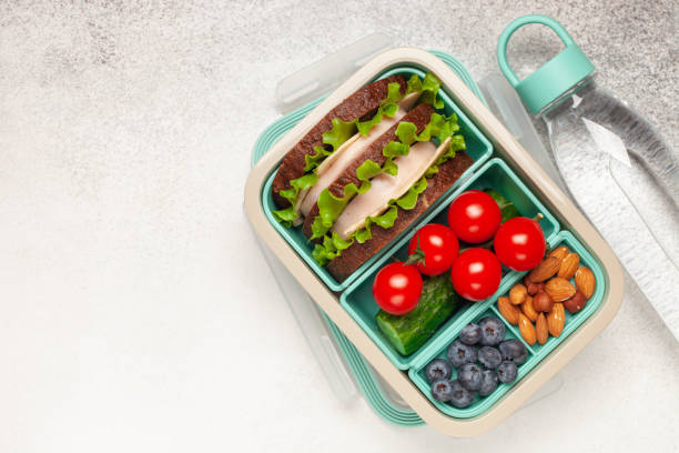 istock School lunch box. Ham and cheese sandwich, vegetables, nuts and berries in a plastic container. Top view. Back to school concept. Copy space 2162883528