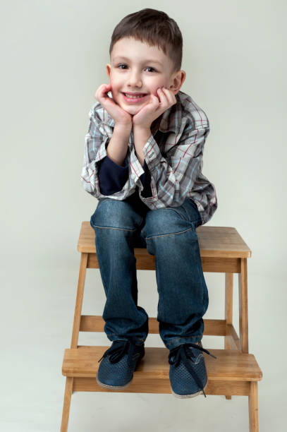 istock A boy sitting on a small ladder thinks and dreams with his head in his hands 2162883641