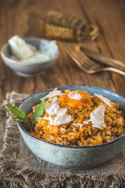Homemade pumpkin risotto with parmesan cheese on a rustic wooden table, vertical