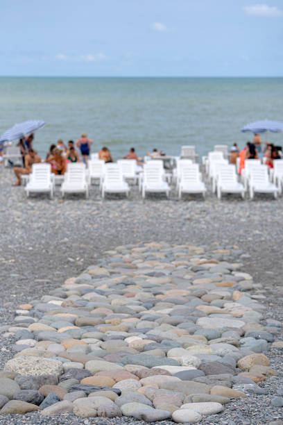 Detail of Pile of stones on the calm beach and tourist couple walking on the beach ,Vacation concept