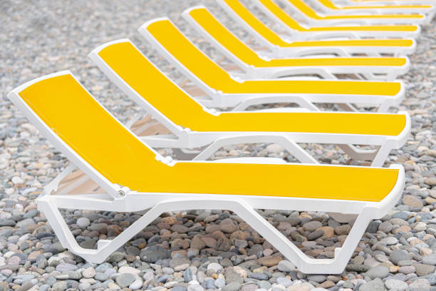 Yellow sun loungers on a pebble beach.