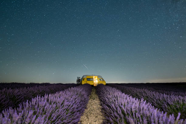 Retro yellow camper van parked under the starry sky in Valensole lavender fields in Provence, France