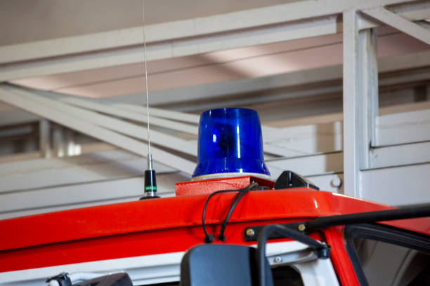 A close-up of a red fire truck reveals the flashing light prominently displayed on top, casting a bright, pulsating glow that signals the truck's presence during emergencies