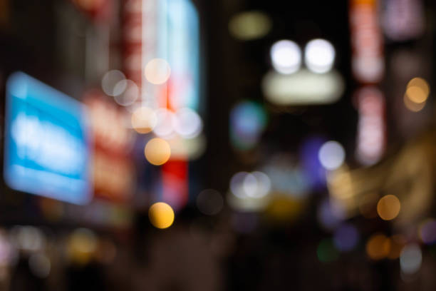 Blurred bokeh background of nightlife city with crowd and billboard