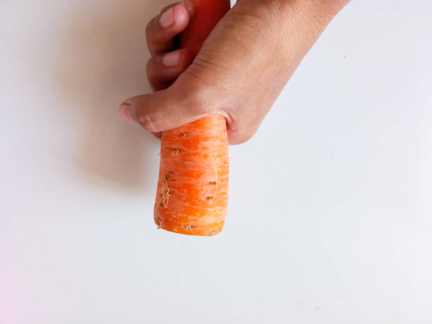 istock Asian woman's hand holding carrot source of vitamin A isolate on white 2162901324