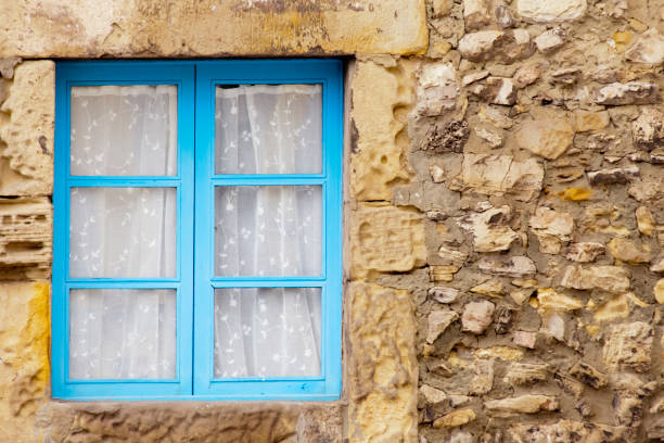 Old weathered stone house facade , blue window, curtain. Copy space on the right. Gijón, Asturias, Spain.