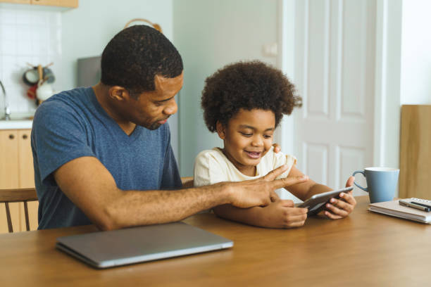 istock Black African American African American Father and son using tablet together at kitchen table, bonding over technology and having fun with a digital device. 2162905223