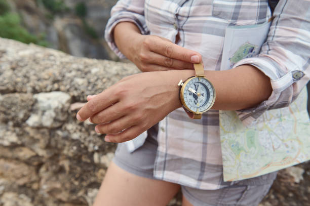 Close-up of a traveler's hands holding a compass watch with a map in the background. Ideal for themes of adventure, exploration, and outdoor navigation.