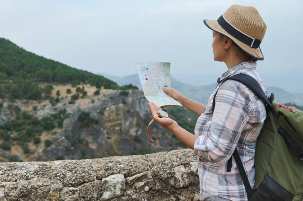 istock Woman with backpack and hat exploring nature with map in hand, enjoying scenic mountain view 2162905866
