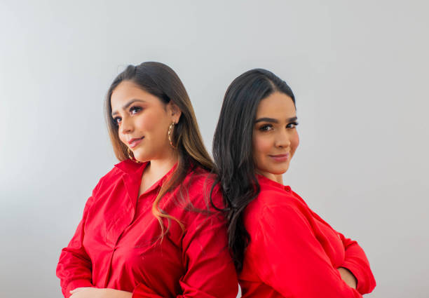 young hispanic latin women together back to back and wearing colorful clothes while smiling