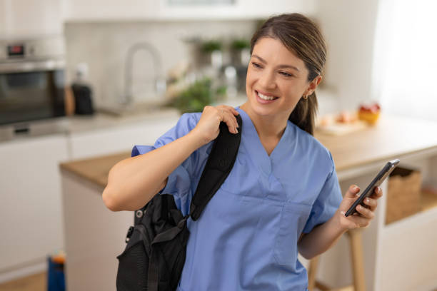 istock Nurse with backpack in kitchen smiling at phone. 2162920963