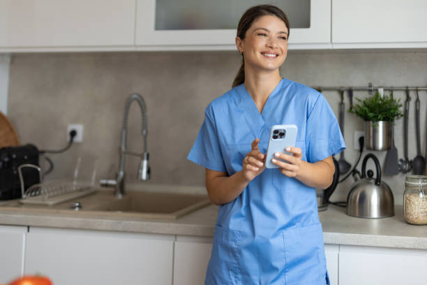 istock Happy nurse in blue scrubs holding phone in kitchen. 2162920996