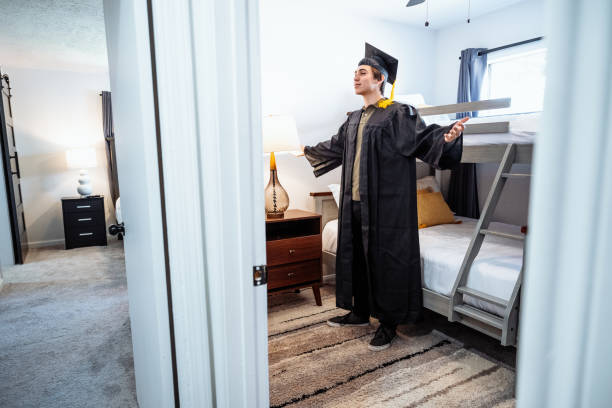 istock Graduation celebration - grad student putting his gown and cap on 2162924449