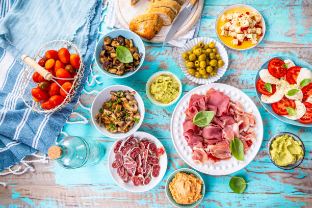 istock Picnic table with assorted appetizers, raw vegetables, cheese, dips, baguette and pastrami and serrano platter 2162925966