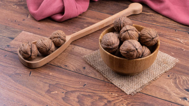 walnut in a spoon on wooden surface. Rustic wooden backdrop.