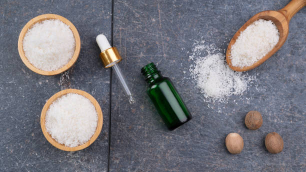 coconut oil bottle with fresh coconut powder on a grey surface.
