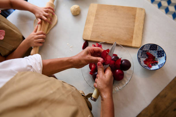 Top view of family cooking together in the kitchen, preparing fruit pie with fresh ingredients and teamwork