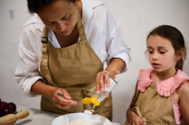 istock Mother and daughter baking together in the kitchen, preparing ingredients 2162933572