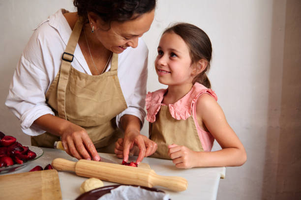 istock Mother and daughter smiling while baking together in kitchen wearing aprons 2162933658
