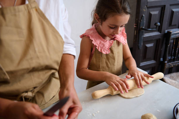 istock Mother and daughter baking in the kitchen together, rolling out dough and bonding 2162934236