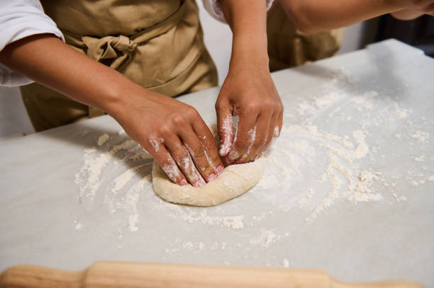 istock Close-up of hands kneading dough on a floured surface in kitchen 2162934249