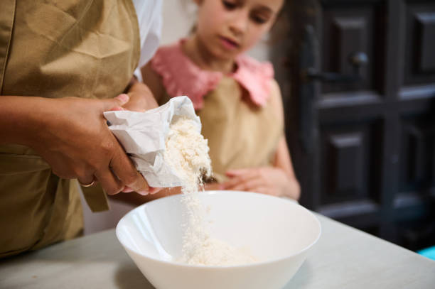 Parent and child baking together, pouring flour into a bowl in a cozy kitchen setting