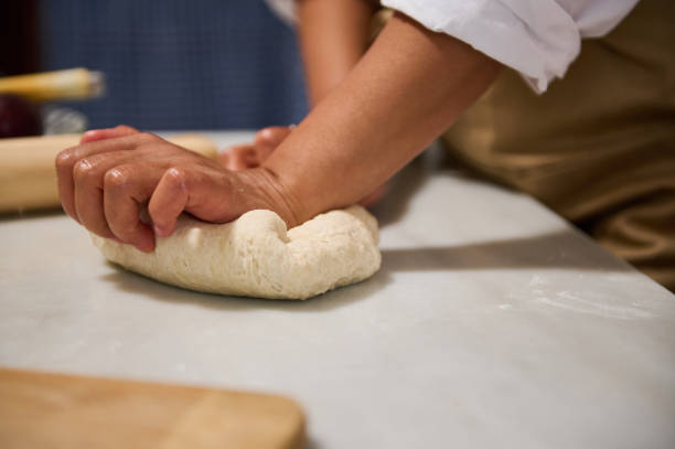 istock Close-up of hands kneading dough on a kitchen counter during baking 2162935481
