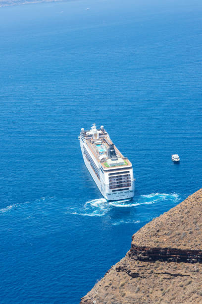 A ship and a boat are docked in the harbor of Muscat, Oman on a sunny day.