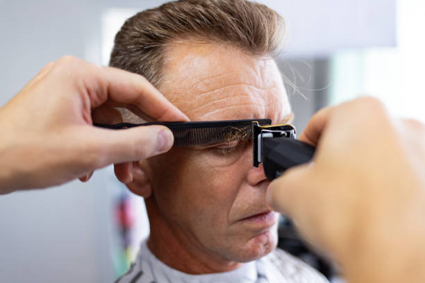 istock Mature man getting his eyebrows trimmed with a hair clipper in a salon. 2162937055
