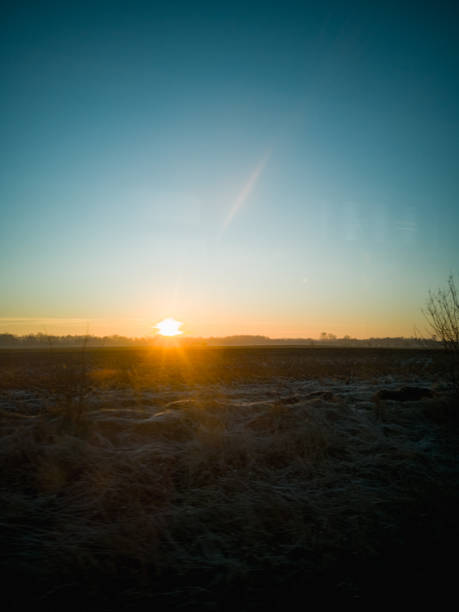 Rising sun from behind the horizon at cold morning seen from train