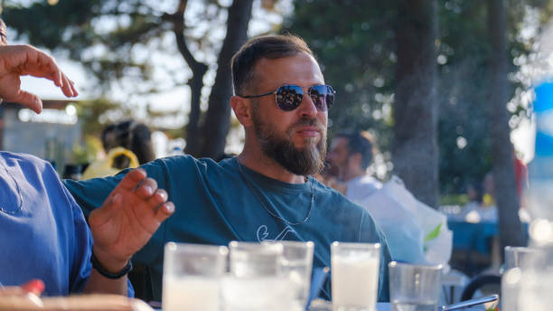 istock Handsome man smiling while posing with drink in hand at picnic table 2162937783