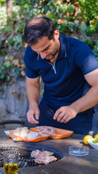 A middle-aged attractive man grilling at a picnic table in a garden on a summer day