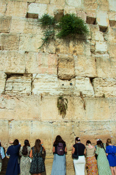 A man presses his hand against the smooth textured stones of the Western Wall while praying in Jerusalem.