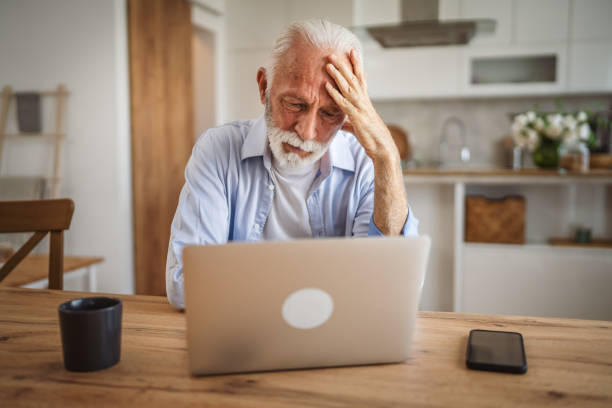 istock Senior man with headache or migraine sit at kitchen and use laptop 2162944018