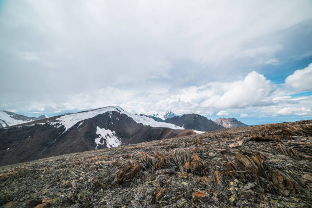 istock Sharp stones on high stony mountain pass with panoramic view to big glacier tongue among rockies and large snow-capped pinnacle in cloudy sky. Spectacular alpine landscape in high rocky snow mountains 2162946201