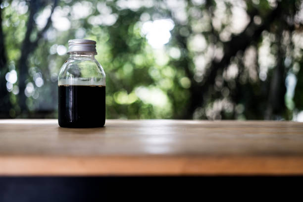 Iced cold brew coffee in blank bottle with lid on wood table.