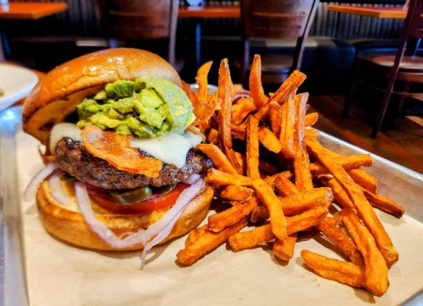 Homemade hamburger with slice of avocado,tomato  and fried potatos .