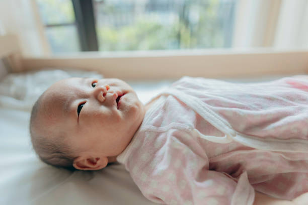 istock A baby girl is lying on the changing table while her mother is changing her clothes, performing infant care and grooming tasks. 2162960052