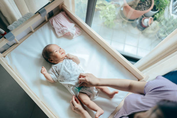 From a high angle, a mother is changing her newborn's clothes, attending to the child's care needs.