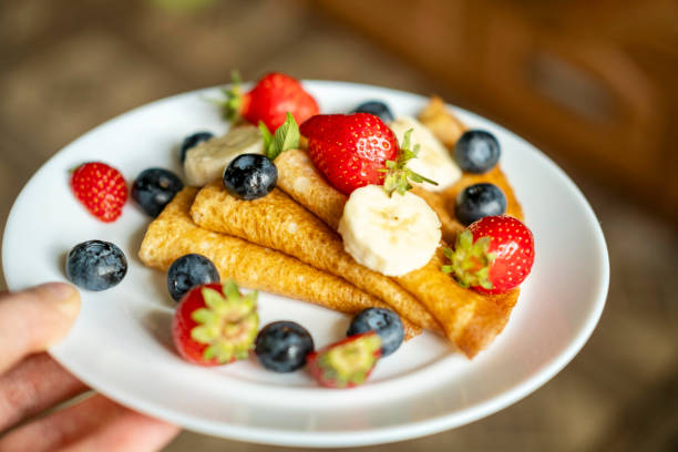istock Plate with sugarless rye flour pancakes decorated with berries in a man's hand. 2162963152