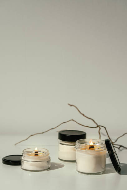 istock Glass Jar Candles Burning on White Tabletop With Branch in Sunlight 2162966803