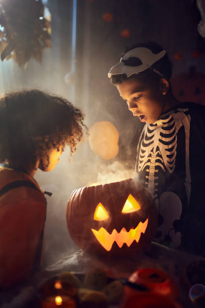 istock Shocked black siblings looking inside of Jack O' Lantern at home. 2162967689