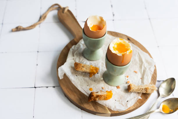 istock Boiled chicken eggs, with liquid yolk and toasted breadd, on egg cups on a white tiled background. Healthy breakfast 2162969593